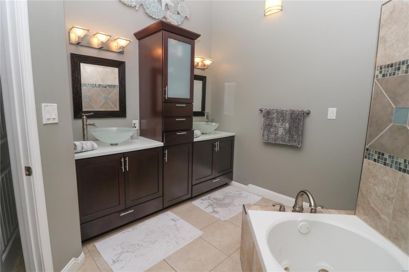 Bathroom with tile patterned floors, a whirlpool tub, double vanity, and a sink