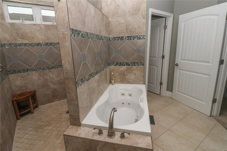Bathroom with tile patterned floors, walk in shower, and a jetted tub