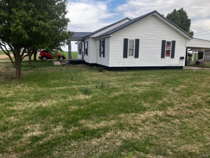 Back of house featuring a lawn and a carport