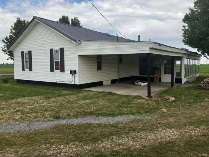 Back of house with a lawn, a sunroom, and metal roof