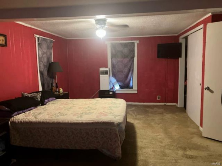 Carpeted bedroom featuring a ceiling fan, baseboards, and ornamental molding