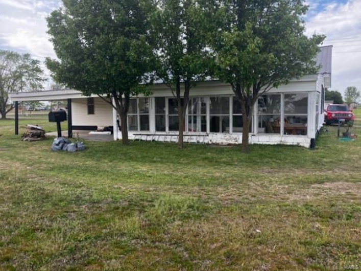 Rear view of house featuring a lawn, a sunroom, and an attached carport