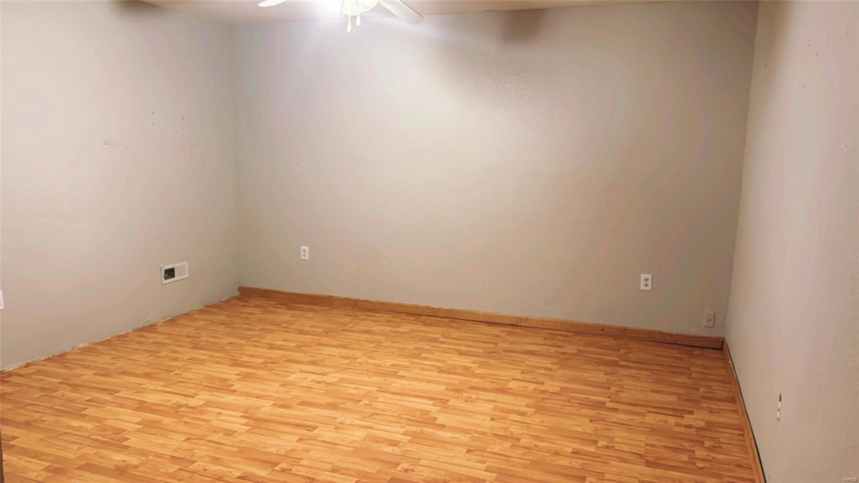 Spare room with light wood finished floors, visible vents, and ceiling fan