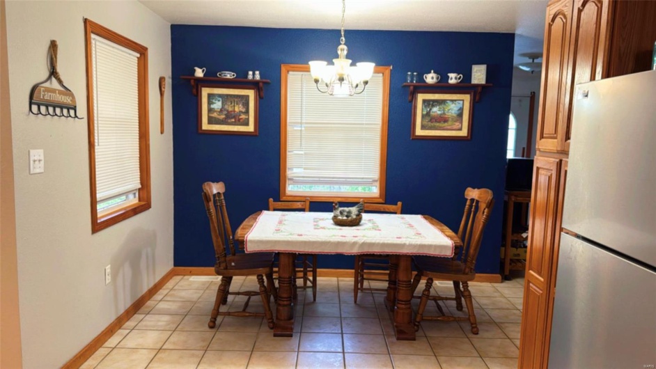 Dining room featuring light tile patterned flooring, baseboards, and a notable chandelier