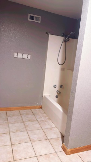 Bathroom with baseboards, tile patterned flooring, shower / bath combination, and visible vents