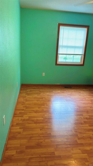 Unfurnished room with wood finished floors, visible vents, and baseboards