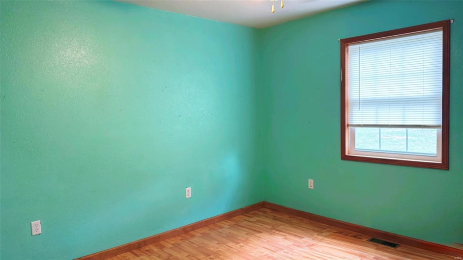 Unfurnished room featuring ceiling fan, baseboards, visible vents, and light wood-type flooring