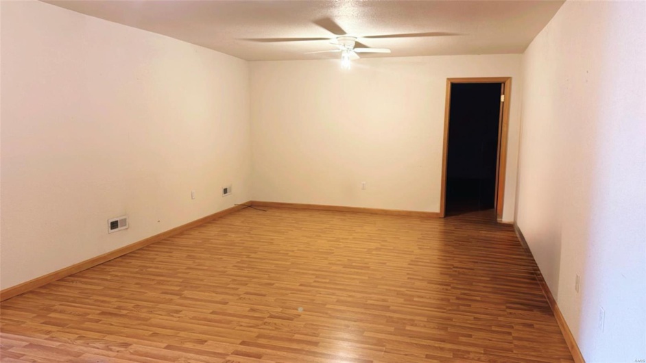 Empty room with light wood-style floors, visible vents, a ceiling fan, and baseboards