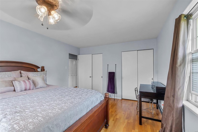 Bedroom featuring light wood finished floors, multiple closets, and a ceiling fan