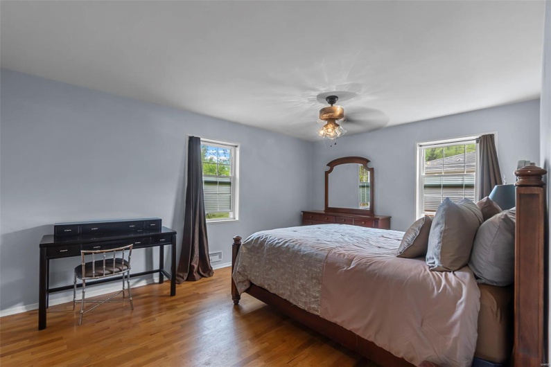 Bedroom featuring baseboards, wood finished floors, and multiple windows