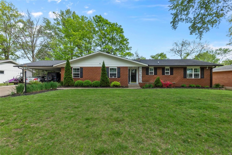 Ranch-style home featuring a front lawn, an attached carport, concrete driveway, brick siding, and entry steps