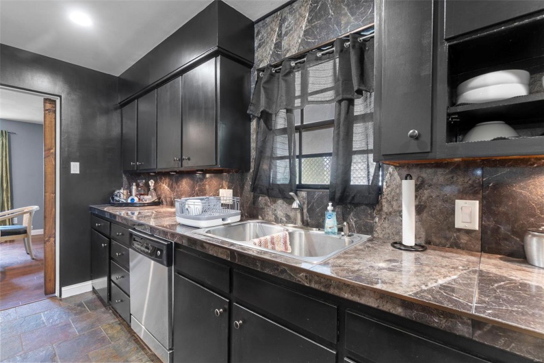 Kitchen featuring dark cabinetry, dishwasher, a sink, and tasteful backsplash