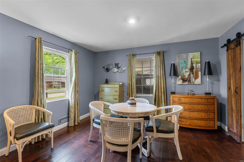 Dining area with baseboards, wood finished floors, and a barn door