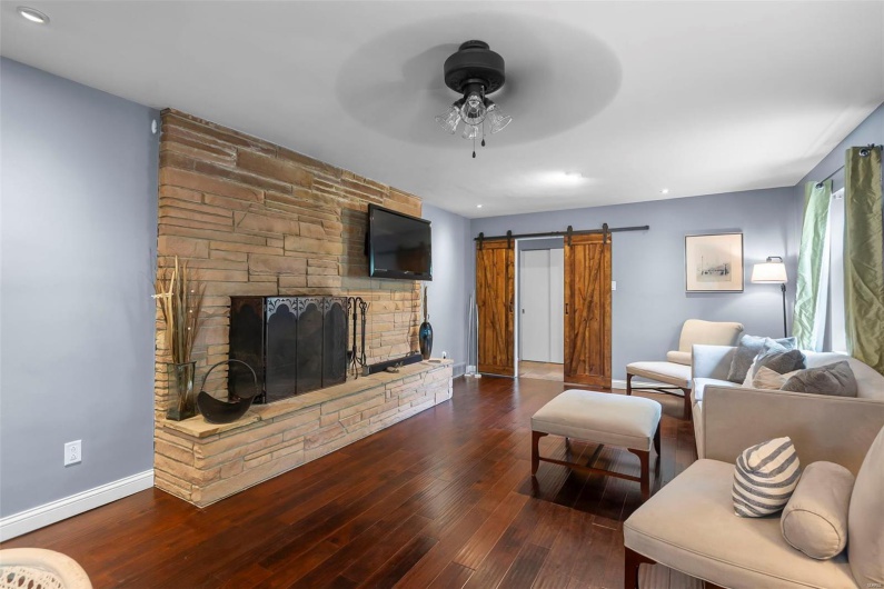 Living room featuring hardwood / wood-style flooring, a barn door, baseboards, and a ceiling fan