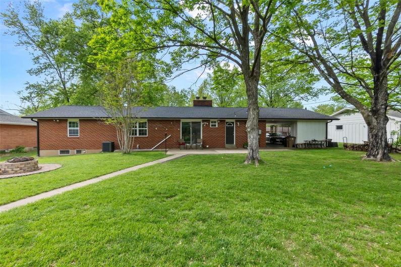View of front of home with a fire pit, a patio, central AC, and a front yard