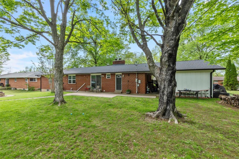 Rear view of house featuring brick siding, a yard, a chimney, and a patio