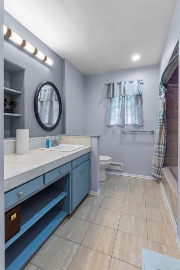 Full bathroom with shower / bath combo, baseboards, toilet, and vanity