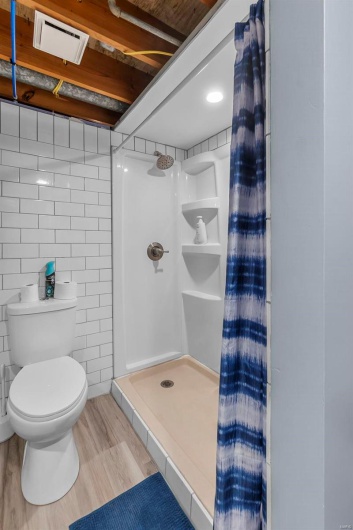 Full bathroom featuring toilet, wood finished floors, and a stall shower