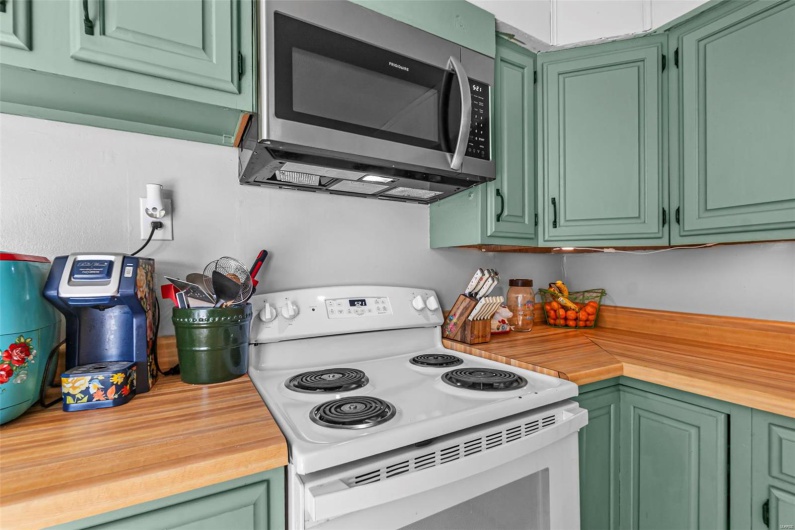 Kitchen featuring stainless steel microwave, butcher block counters, and white electric range oven