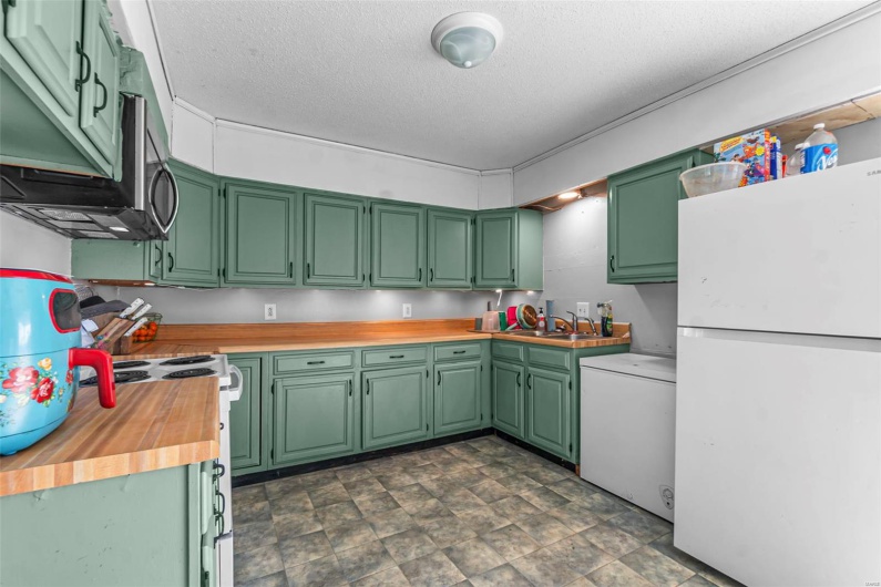 Kitchen with butcher block counters, a textured ceiling, a sink, and white appliances