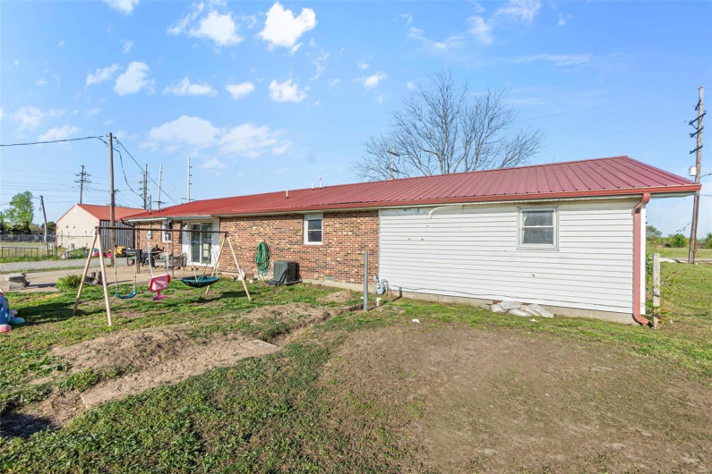 Back of house with central air condition unit, fence, and metal roof