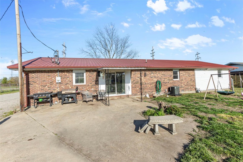 Back of house with brick siding, cooling unit, and metal roof