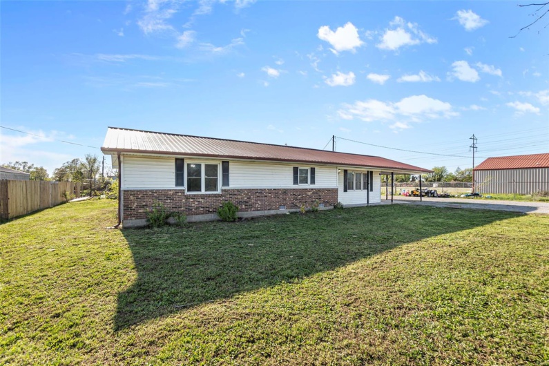 View of front of property featuring fence, a front lawn, and metal roof