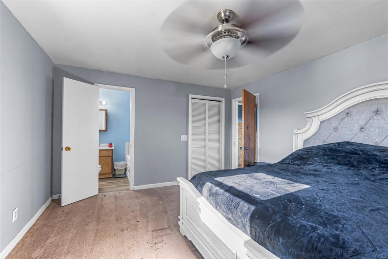 Bedroom with light carpet, ensuite bathroom, baseboards, and a closet