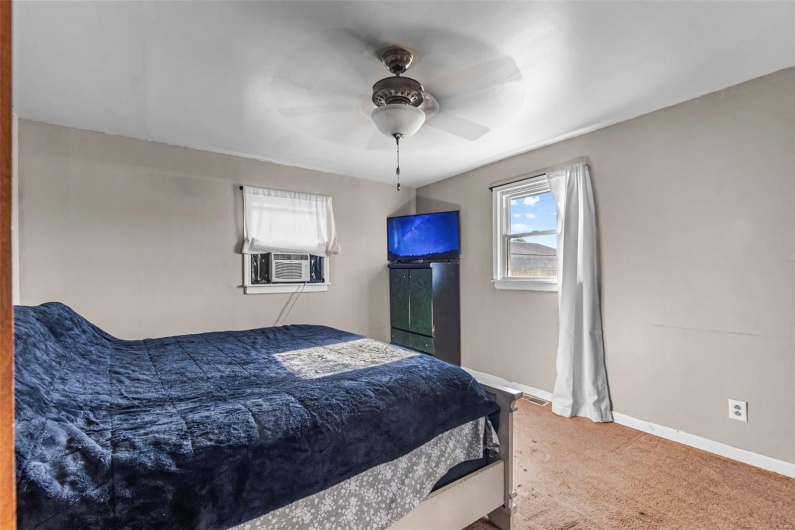 Bedroom featuring ceiling fan, baseboards, carpet flooring, and cooling unit