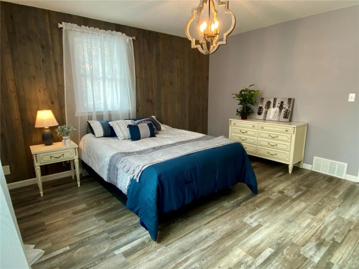 Bedroom with wooden walls, a chandelier, and hardwood / wood-style flooring
