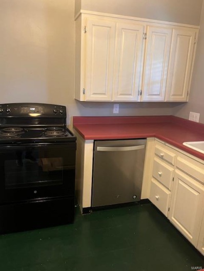 Kitchen with black dishwasher, range, and white cabinets