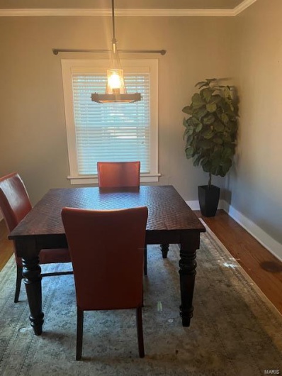 Dining area with a notable chandelier, crown molding, and hardwood / wood-style flooring