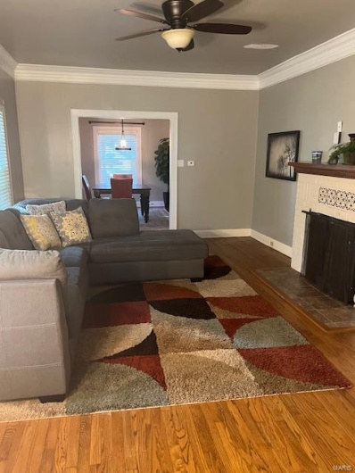 Living room featuring crown molding, dark hardwood / wood-style floors, and ceiling fan