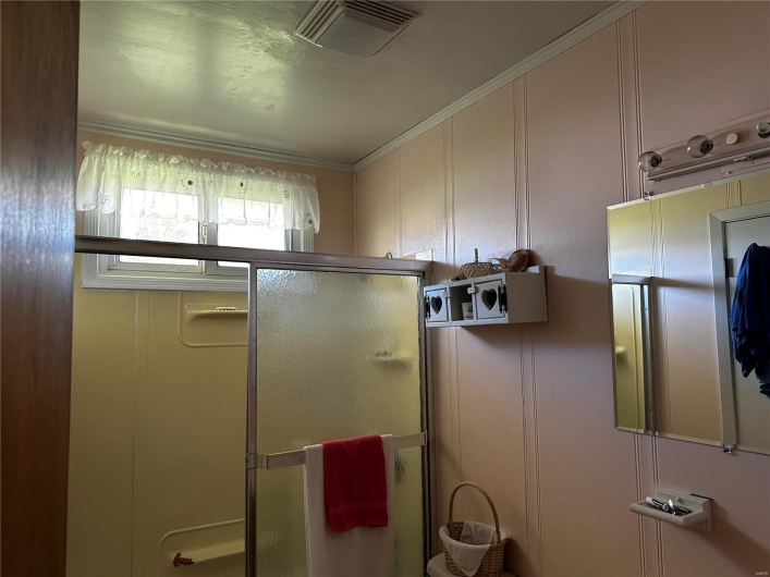 Bathroom with ornamental molding and walk in shower