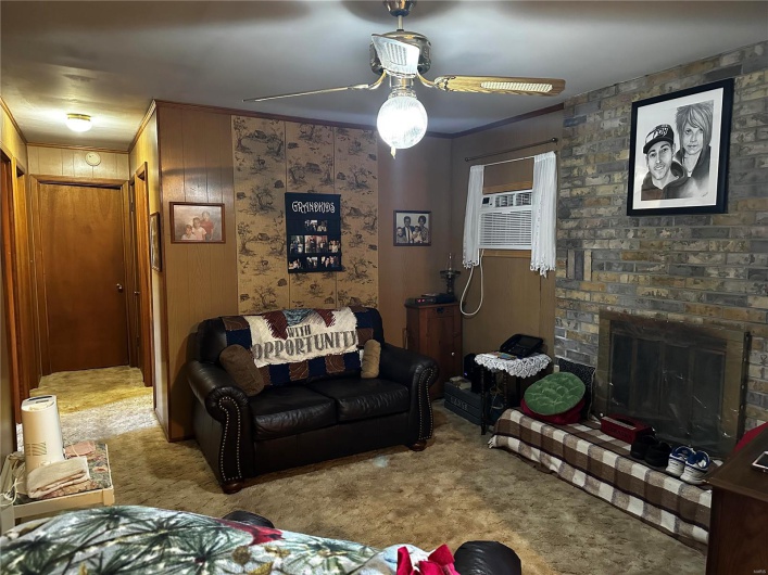 Carpeted living room with a wall unit AC and a fireplace