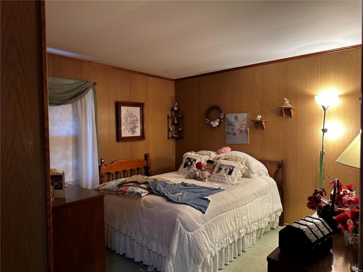 Bedroom with ornamental molding and wood walls