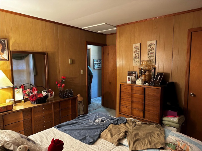 Bedroom featuring ornamental molding and wood walls