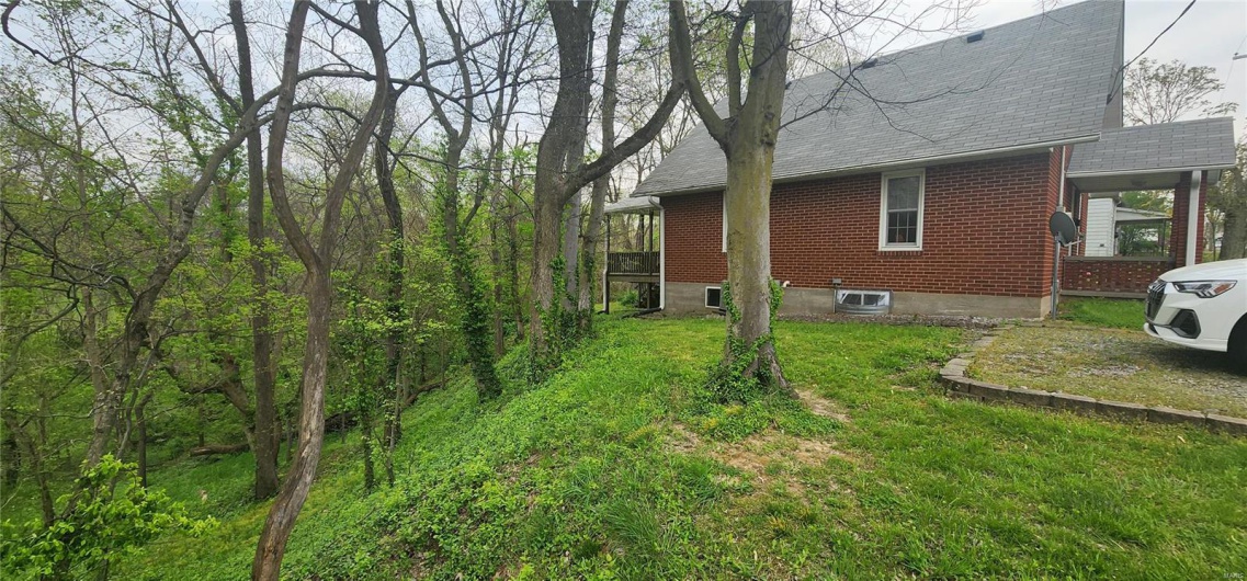 View of home's exterior featuring roof with shingles, brick siding, and a yard