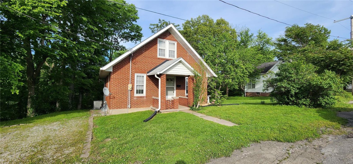 Bungalow with a front yard and brick siding