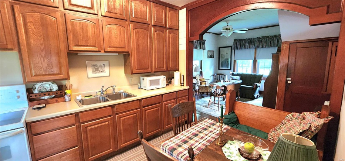 Kitchen with a sink, white microwave, a ceiling fan, and light countertops