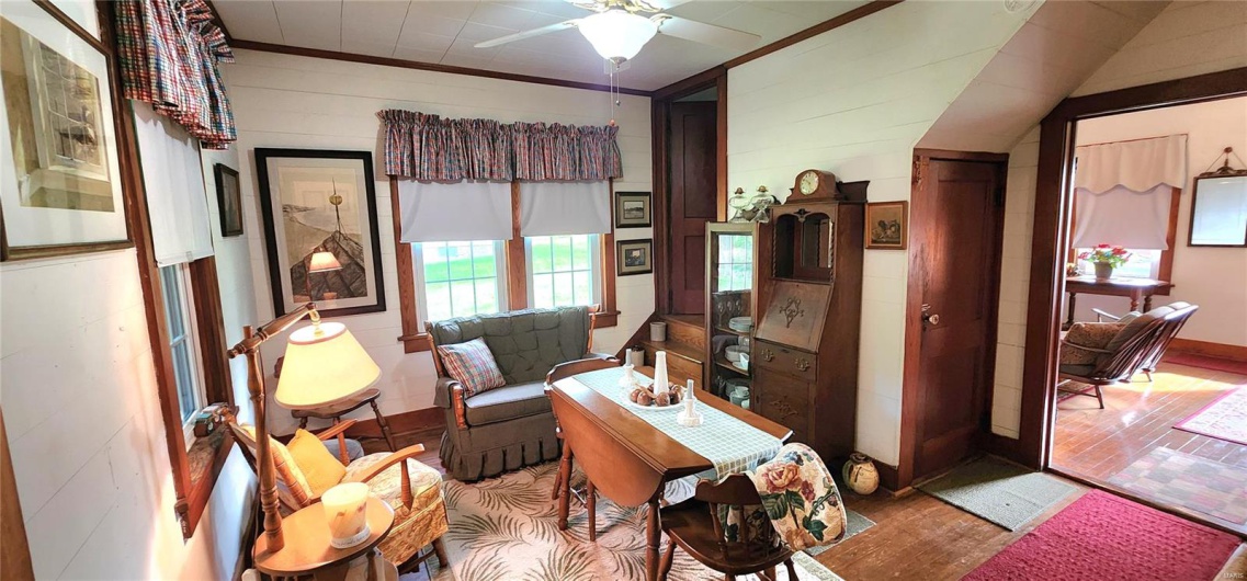 Living area featuring wood finished floors, ceiling fan, crown molding, wood walls, and baseboards
