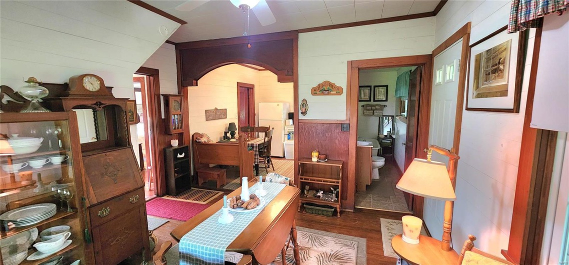 Office featuring wood walls, arched walkways, ceiling fan, and wood finished floors