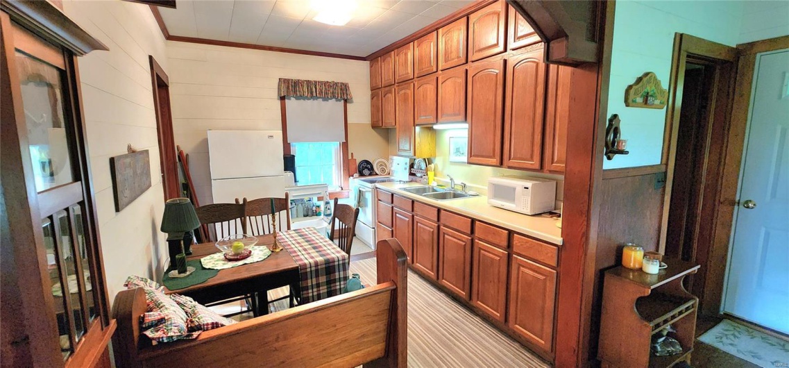 Kitchen featuring a sink, light countertops, ornamental molding, white appliances, and brown cabinetry