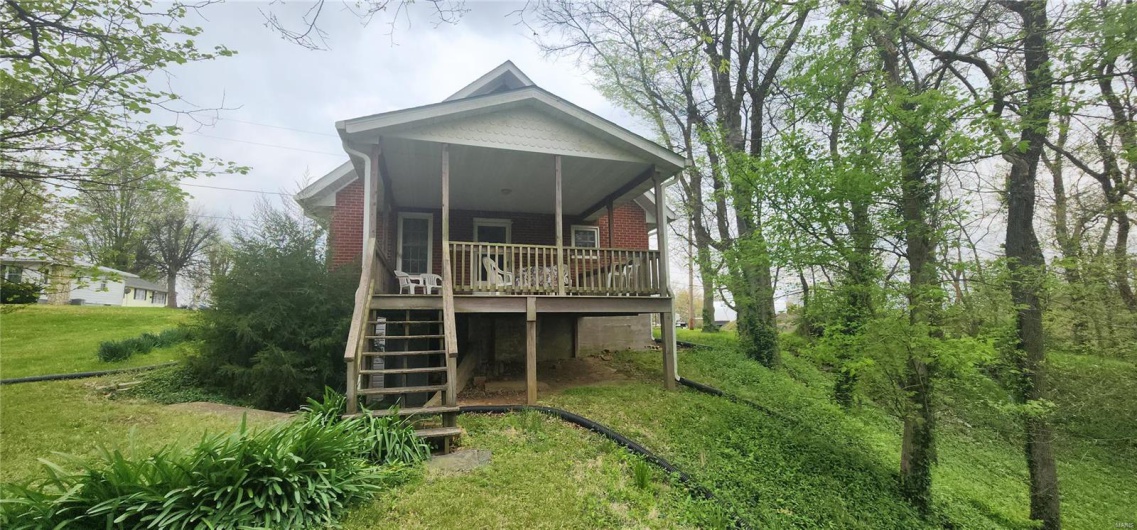 Rear view of property with brick siding, stairway, and a deck