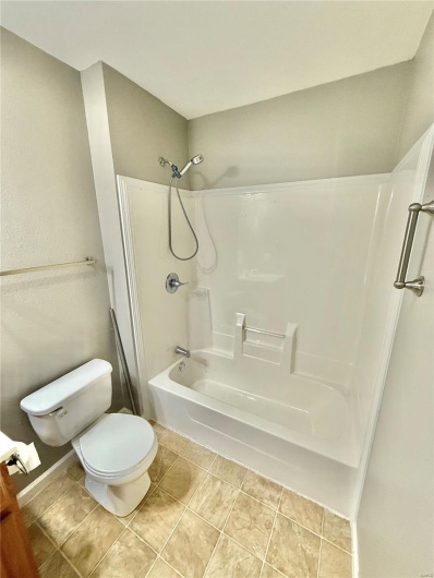 Bathroom featuring toilet, tile patterned flooring, and tub / shower combination