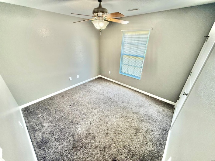 Carpeted empty room with ceiling fan, baseboards, and visible vents