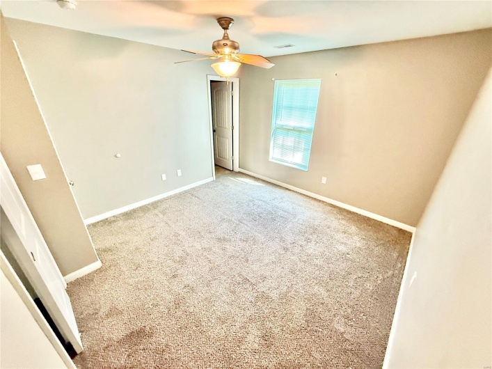 Unfurnished bedroom featuring baseboards, a ceiling fan, visible vents, and carpet