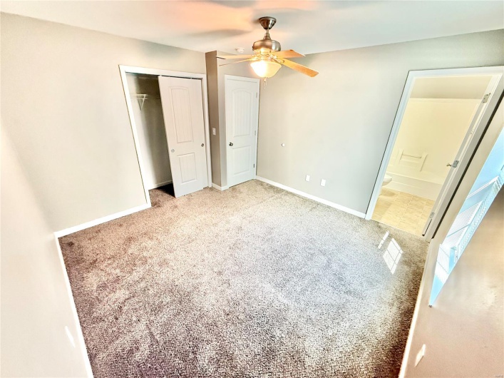 Unfurnished bedroom with ensuite bath, carpet flooring, a closet, and a ceiling fan