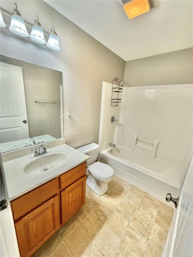 Full bath with visible vents, toilet, vanity, and shower / tub combination