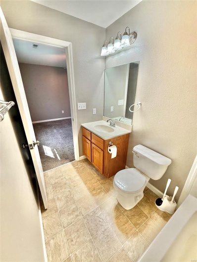 Bathroom featuring toilet, vanity, visible vents, and baseboards